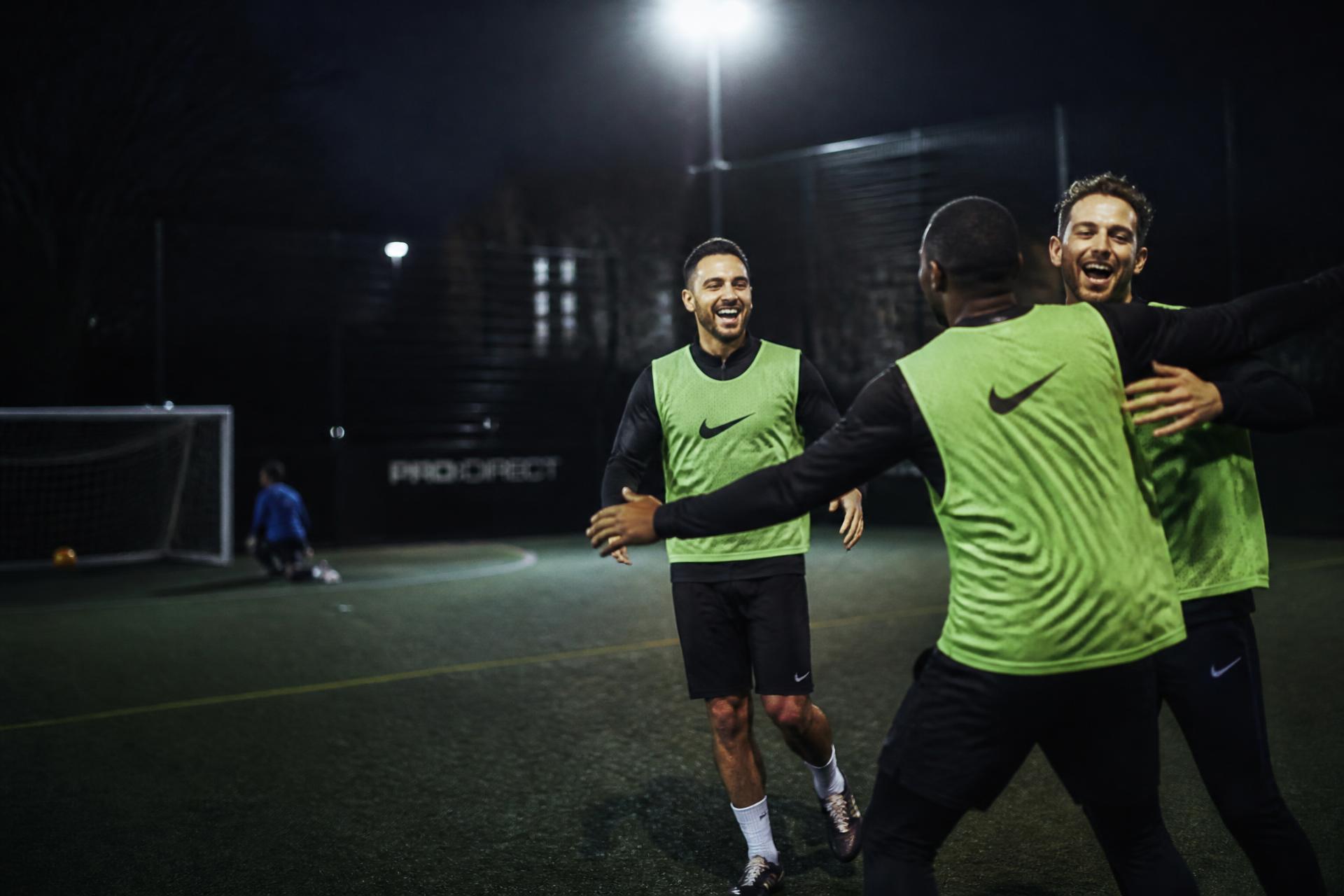 Grassroots football players celebrating under floodlights
